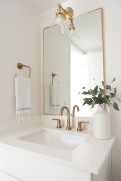 a bathroom sink with a large mirror above it and a vase on the counter next to it