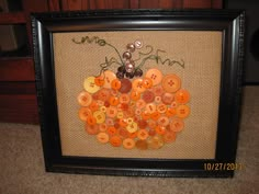 there is a framed picture with buttons in the shape of a pumpkin on burlap