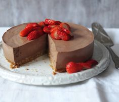 a chocolate cheesecake topped with strawberries on a white plate