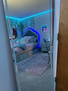 a bedroom with a bed, dresser and mirror in it's corner is lit up by blue lights