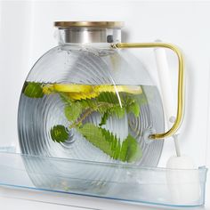 a glass teapot filled with water and green leaves