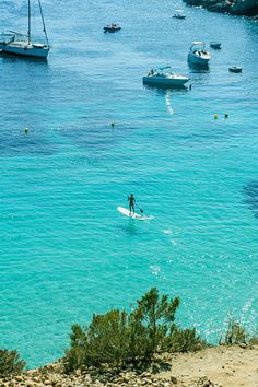 a person on a surfboard in the water with boats and yachts in the background