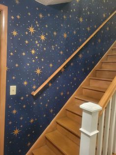 a staircase with stars painted on the wall and wooden handrails in front of it