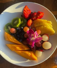 a white plate topped with cut up fruits and veggies on top of a wooden table