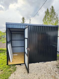 a small black shed sitting on top of a grass covered field