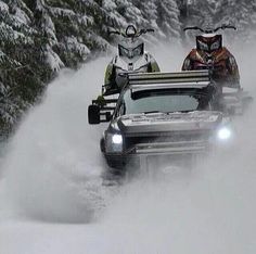 two snowmobiles driving down a snowy road