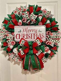 a christmas wreath with candy canes on the front door and merry sign above it