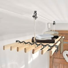 a wooden shelf with clothes hanging from it's hooks and some other items on top