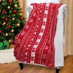 a red and white blanket sitting on top of a chair next to a christmas tree