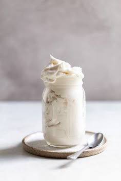 a jar filled with whipped cream sitting on top of a plate next to a spoon