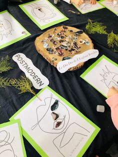 children are drawing faces on paper with markers and pencils at a table covered in cards