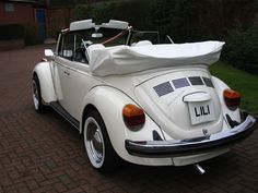 an old white car parked in front of a brick building with a surfboard on the roof