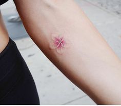 a woman's arm with a small flower tattoo on the left side of her arm