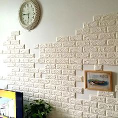 a tv sitting on top of a wooden table in front of a white brick wall