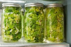 three mason jars filled with different types of salads and greens on a refrigerator shelf