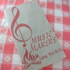 a red and white checkered table cloth with music makers camp fire girls sticker on it