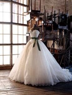 a wedding dress on display in front of a window with an old wagon behind it