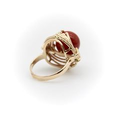 This is part of Chairish’s Fine Jewelry assortment.  At Kirsten’s Corner we love vintage coral, and this ring centers around a 12mm round sphere of well-saturated deep red Sardinian coral. The ball is centered in a tentacle-like circular mount that flows from its base and grasps the coral ball in a beautiful sci-fi fashion.  The 14k gold tentacles have a textured matte surface, ending in tiny golden balls that come together on either side of the sphere like finger tips on a hand. Circa the 1970’s, this is a great conversation piece that is both unique and elegant.   The ring is marked as 14k. It weighs 7.41 grams. The circular element measures 3/4” and the ring rises up 1/2” high on the finger. Made in Italy.   Ring size 5. Formal Red Domed Rings, Red Domed Gemstone Rings, Elegant Red Dome Ring For Formal Occasions, 14k Gold Cabochon Red Ring, 14k Gold Red Cabochon Ring, Elegant Red Dome Ring For Anniversary, 14k Gold Rings With Red Cabochon, Red Domed Rings For Anniversary, Red Domed Anniversary Ring