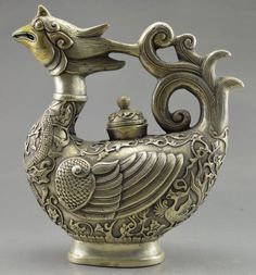 an ornate silver vase with a bird on it