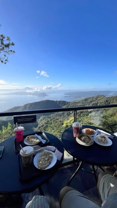 two plates of food sit on top of a table overlooking the water and mountains in the distance