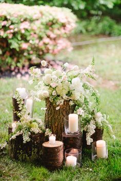 the centerpieces are made out of logs and flowers in vases on the grass