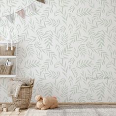 a baby's room with white and green leaves on the wall, rugs and toys