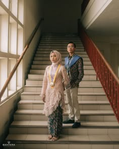 two people standing on the stairs in front of some windows