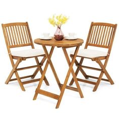 three wooden chairs sitting around a small table with two white cushions on top of it