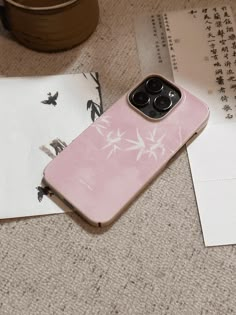 a pink phone case sitting on top of a table next to an envelope and cup