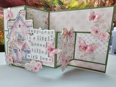 an open card with pink flowers and butterflies on it, sitting on top of a table