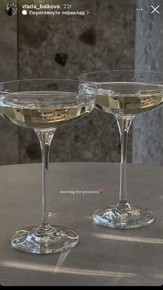 two champagne glasses sitting on top of a table next to each other, one filled with liquid and the other empty