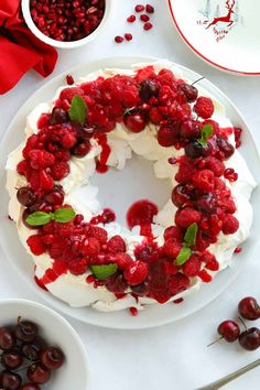 a cake with cherries and whipped cream on it sitting next to bowls of cherries