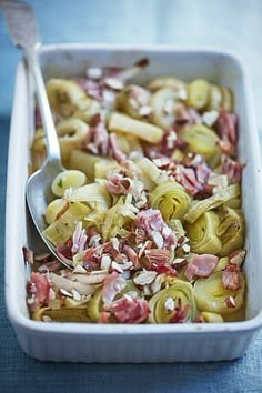 a casserole dish with ham, onions and other toppings in a white baking dish