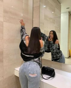 a woman taking a selfie in front of a bathroom mirror with her cell phone