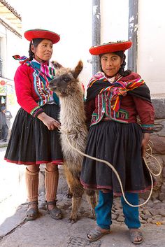 two women in traditional mexican garb with a llama