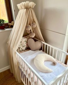 a white crib with a canopy and pillows in it