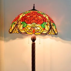 a lamp that is on top of a wooden stand with a flower pattern shade over it