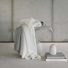 a white vase sitting on top of a table next to a blanket