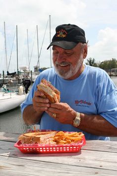 a man sitting at a table with a sandwich and french fries in front of him