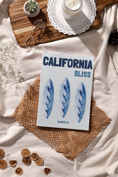 the california bliss magazine is laying on a bed next to some cookies and other items