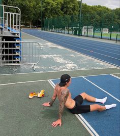 a man laying on the ground next to a tennis court