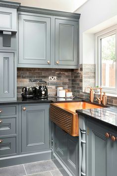 a kitchen with gray cabinets and marble counter tops