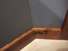 the corner of a room with wood flooring and gray paint on the wall behind it