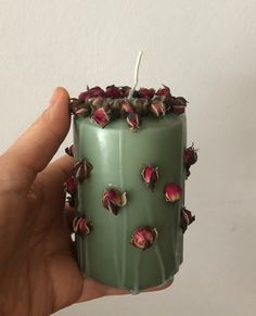 a hand holding a green candle with pink flowers on it