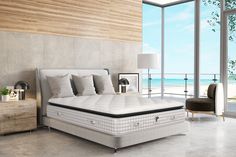 a bedroom with a bed, nightstands and windows overlooking the beach in front of it