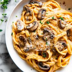 pasta with mushrooms and parmesan cheese in a white bowl on a marble table