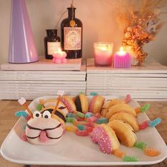 a plate with donuts and doughnuts on it next to candles, bottles and flowers