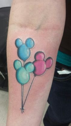 a mickey mouse tattoo on the arm with balloons attached to it's back legs