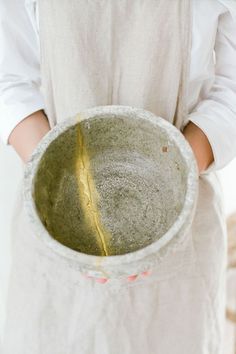 a person holding a bowl with yellow substance in it's hands and wearing a white shirt