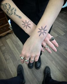 two people are holding hands with tattoos on their arms and one has an arrow in the middle